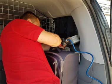 Our technician stamps & certifies the aftermarket window laminates Technician working in rear of vehicle